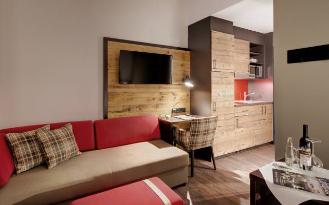 Der gemütlich-eingerichtete Wohnbereich einer Suite im Hotel Traumschmiede mit einer großen Couch und einer Küchenzeile