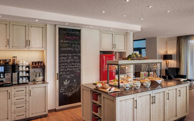 Im Frühstücksraum des Hotels Traumschmiede hängt neben einem Buffet mit der Kaffeemaschine eine große Tafel, auf der einige Empfehlungen stehen