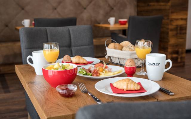 Frühstücken im Hotel Traumschmiede: mehrere Teller mit Obstsalat, Crossaints und Semmeln stehen auf einem Frühstückstisch