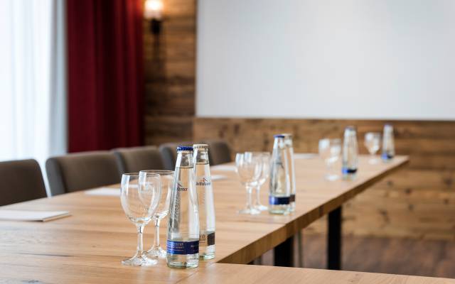 Im Tagungsraum des Hotels Traumschmiede stehen auf einem Konferenztisch mehrere Wasserflaschen und Gläser