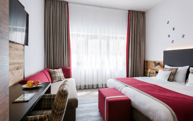 Ein Zimmer im Hotel Traumschmiede mit viel Tageslicht durchflutet mit Boxspringbett, Couch und Schreibtisch